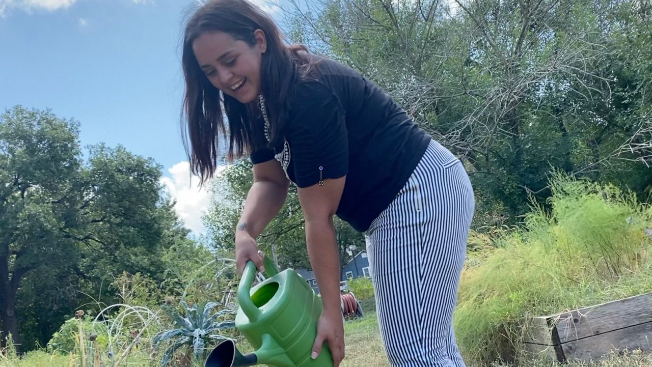 Ashley Leonard waters plants in this image from August 2021. (Spectrum News 1/Olivia Levada)
